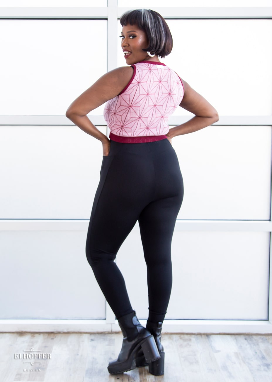 Lynsi, a medium dark skinned model with short dark brown hair with white highlights, is wearing a pair of high waisted leggings with a seamless front and side seam pockets in black.