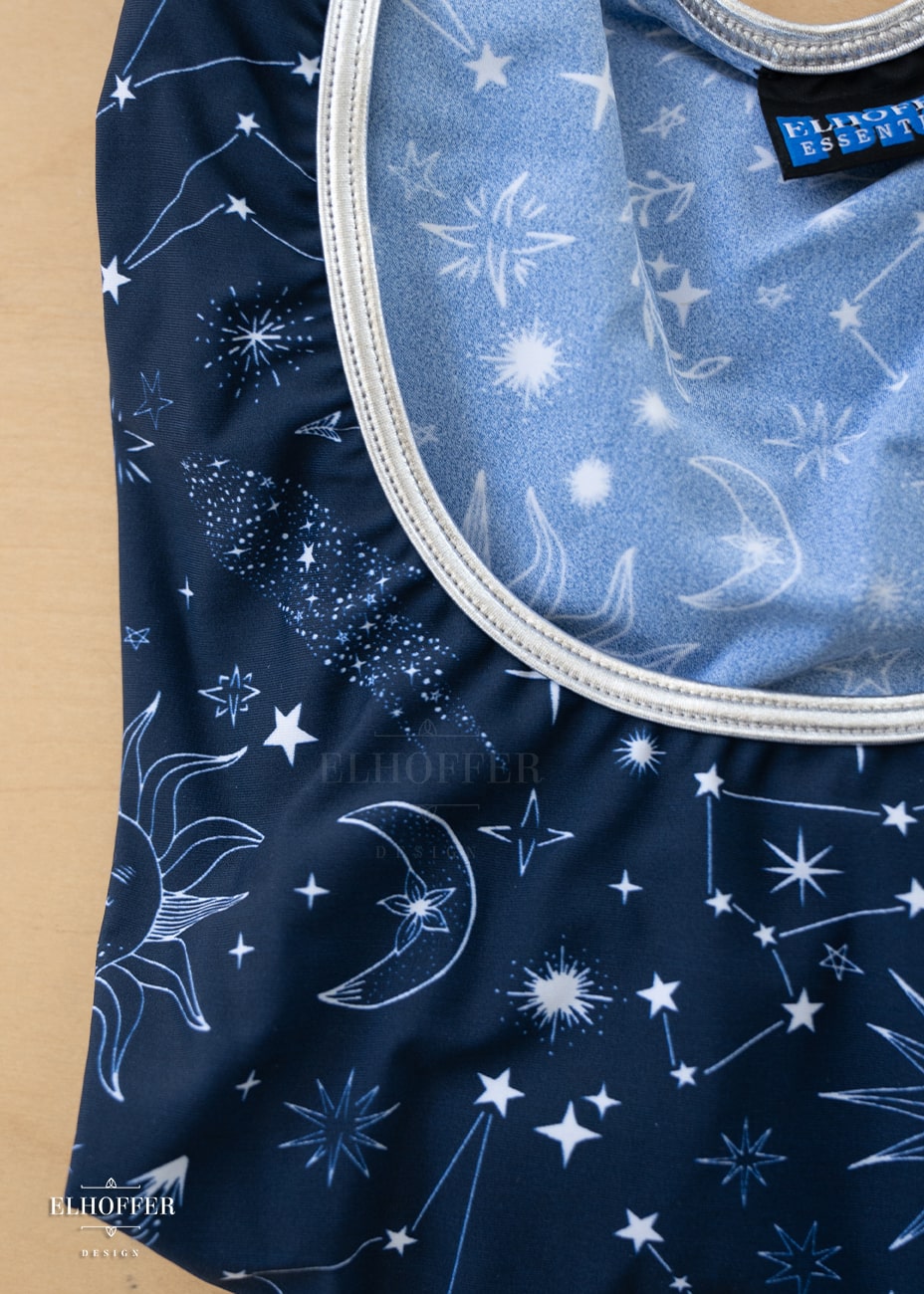 A close up on the silver collar detail and the star crossed lover fabric. The Star-Crossed Lovers print is a celestial inspired pattern featuring a navy base and white stars, constellations, sunds, moons, and other small details scattered across the repeated art.