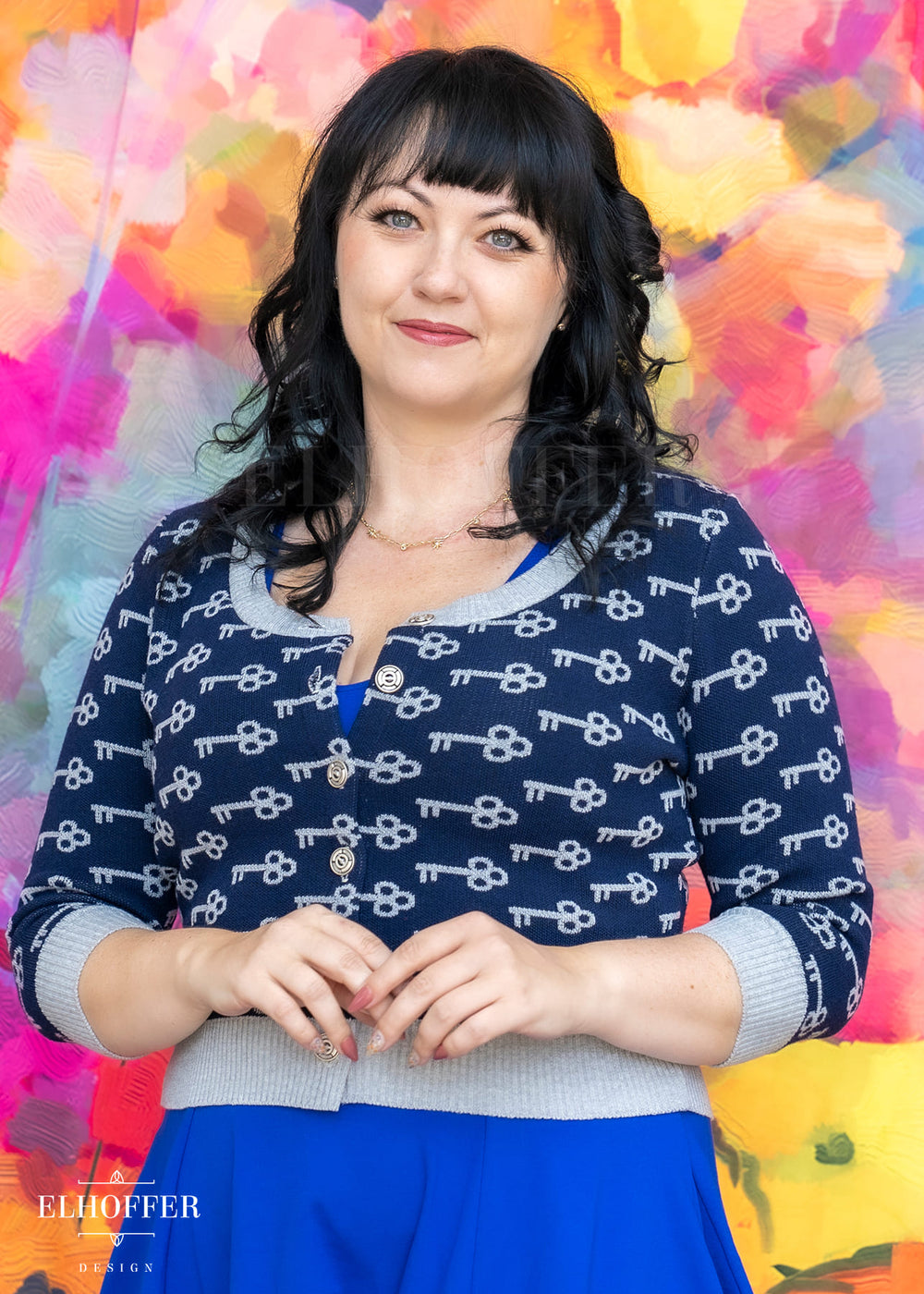 Woman wearing a navy blue sweater with white patterns against a colorful abstract background