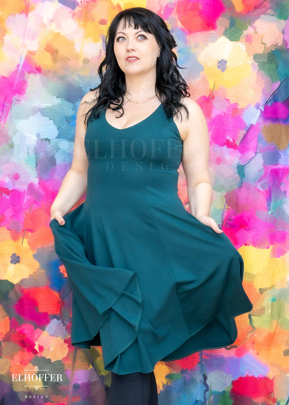 Woman in a teal dress posing against a colorful abstract background with 'Elhoffer Design' branding.