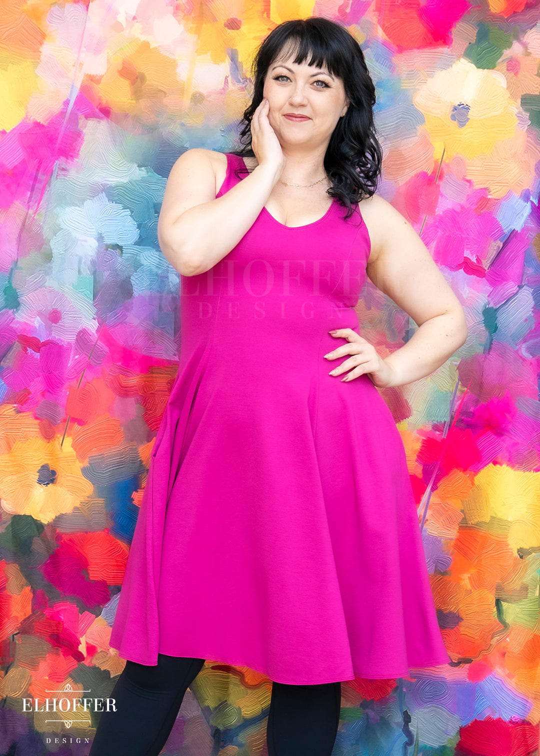 Woman in a pink dress standing against a colorful floral background