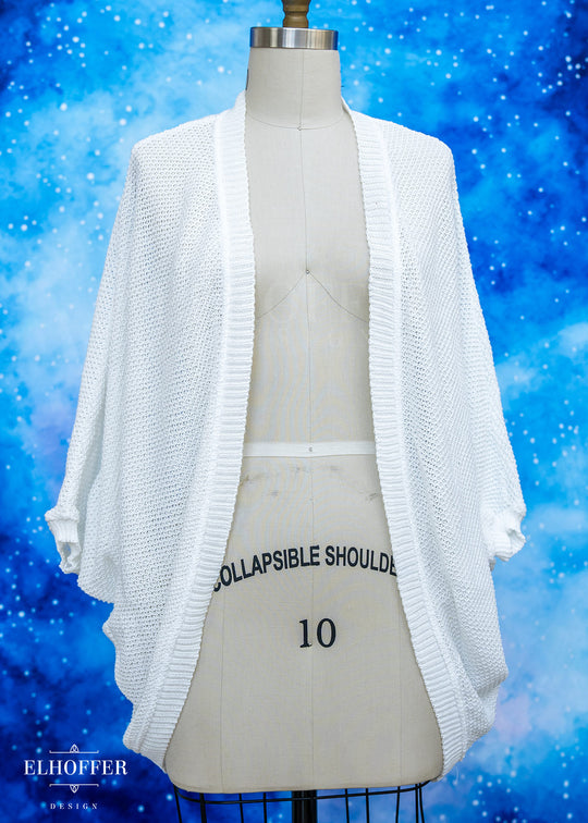 White cardigan on a mannequin against a blue snowy background