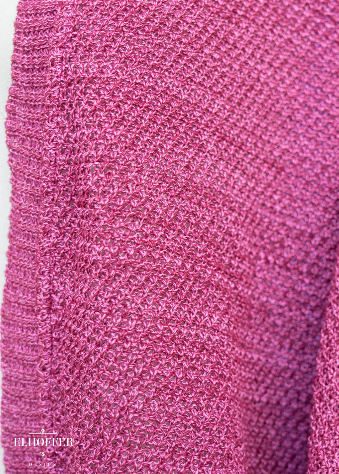 Close-up of a pink textured fabric with a brand name at the bottom.