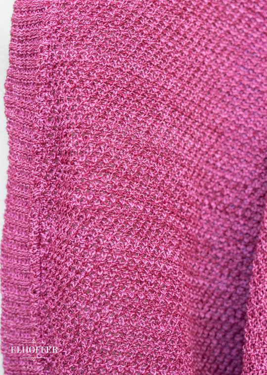 Close-up of a pink textured fabric with a brand name at the bottom.