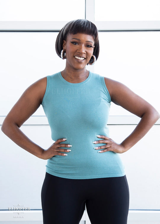 Lynsi, a medium dark skinned model with a dark brown and white bob, is wearing our pullover sleeveless sweater tank in seafoam blue.