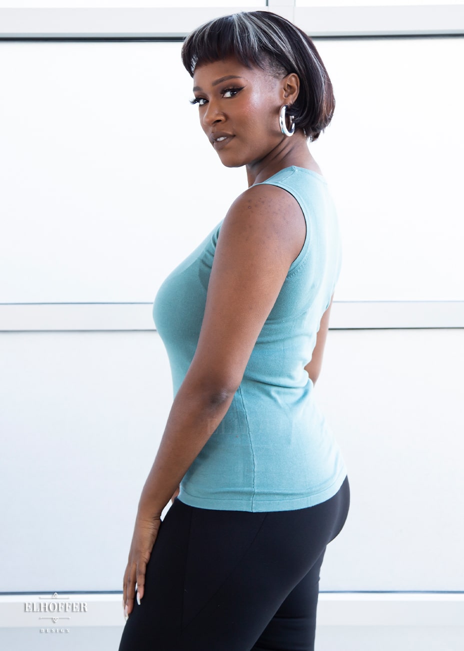 Lynsi, a medium dark skinned model with a dark brown and white bob, is wearing our pullover sleeveless sweater tank in seafoam blue.