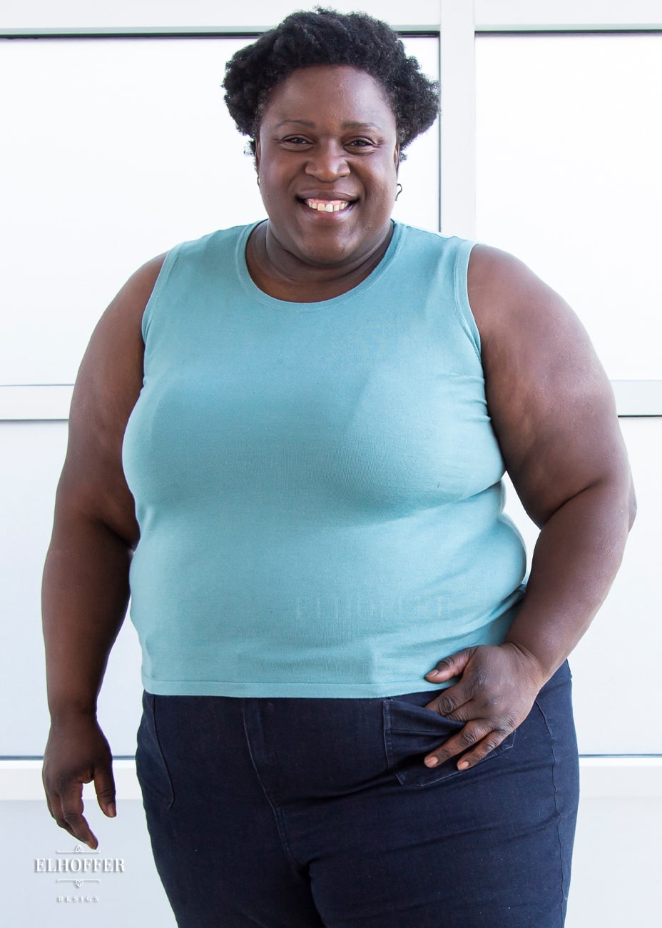 Adalgiza, a dark skinned size 4XL model with short curly black hair,  is wearing our pullover sleeveless sweater tank in seafoam blue.