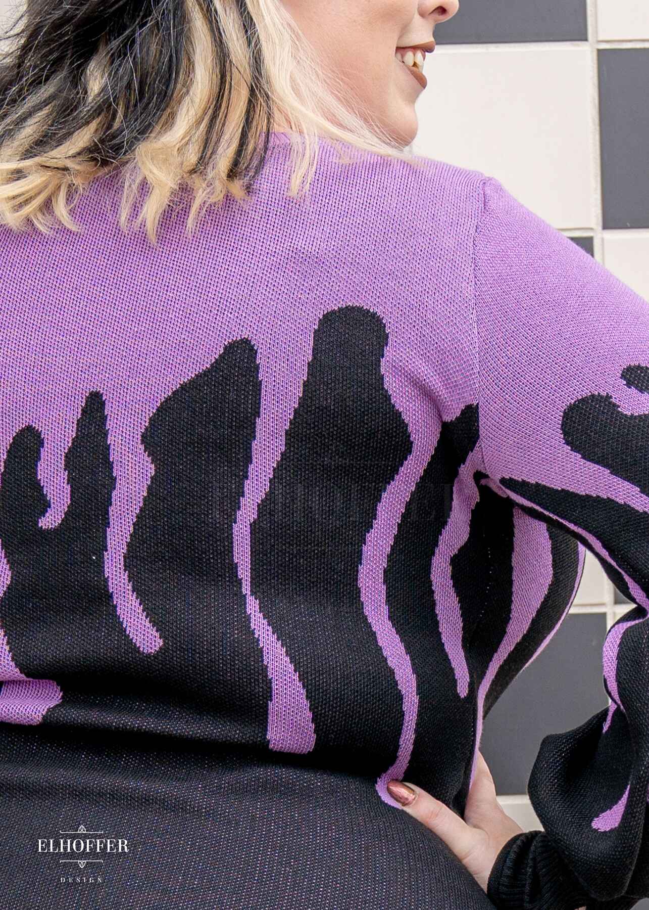 A close up of the lavender purple drip design on the knit sweater