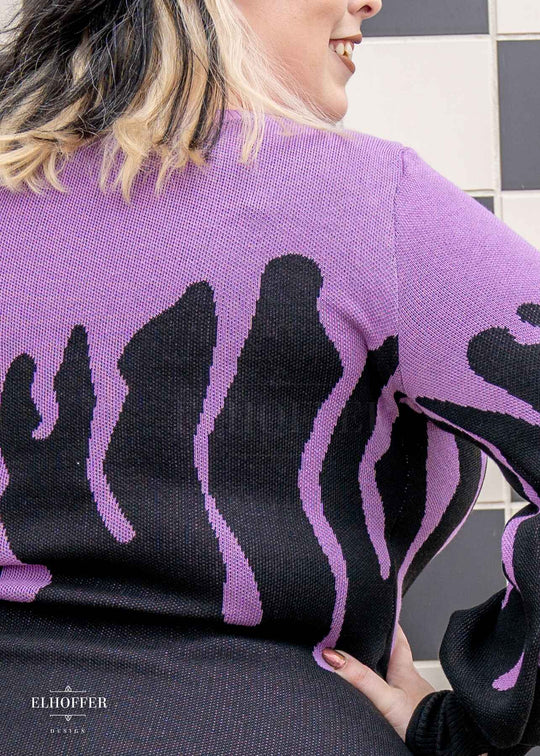 A close up of the lavender purple drip design on the knit sweater