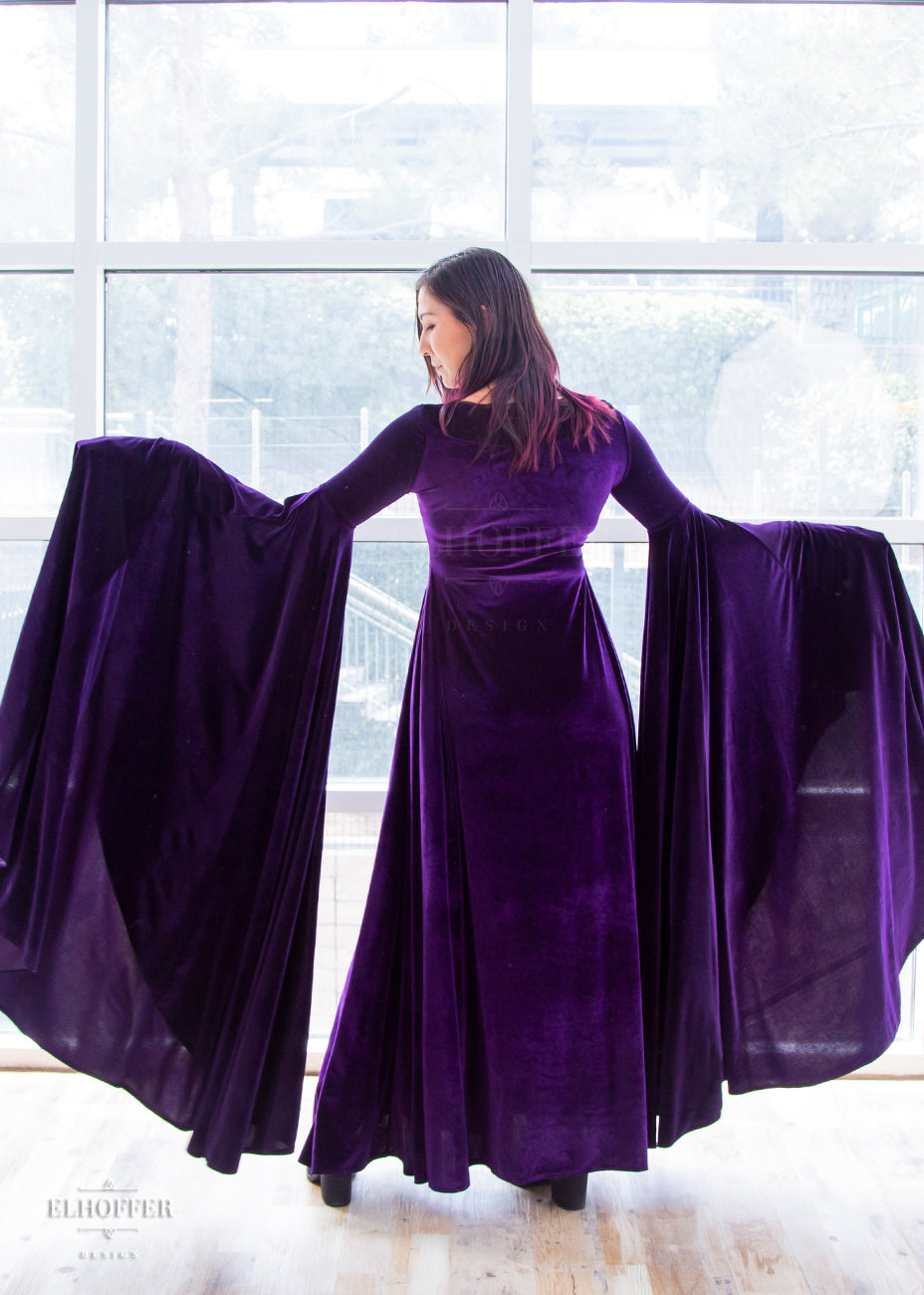 Susan models the back of the full length purple velvet dress. The sleeves are fitted to the elbow and are full and the ends fall to the floor.