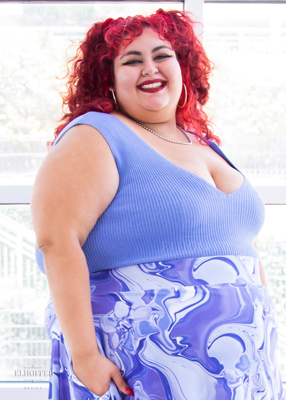 Victoria, an olive skinned size 4XL model with bright red curly hair, is wearing a pullover sleeveless ribbed v-neck tank in light blue. The v-neck is actually reversible and offers two depths.