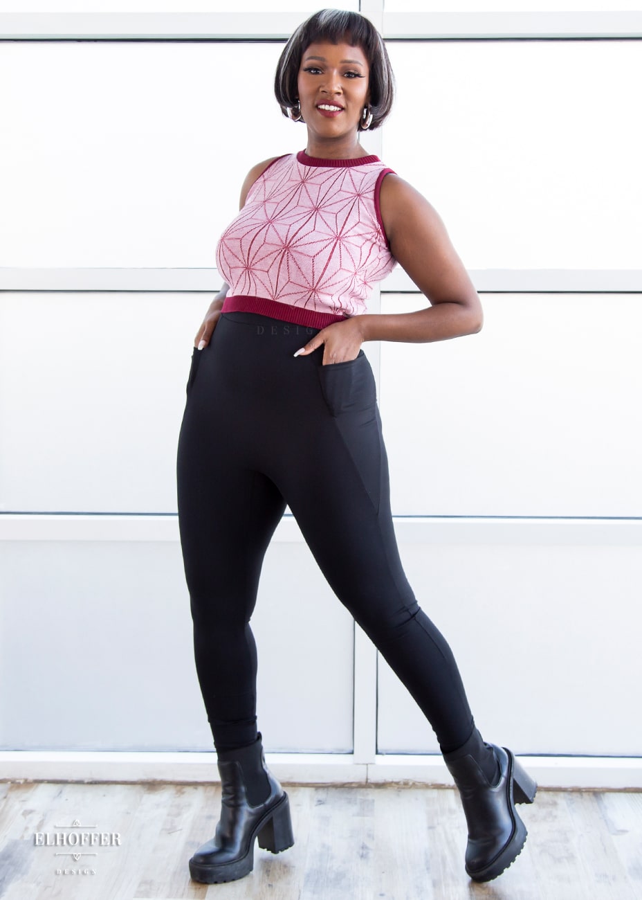Lynsi, a medium dark skinned model with short dark brown hair with white highlights, is wearing a pair of high waisted leggings with a seamless front and side seam pockets in black.