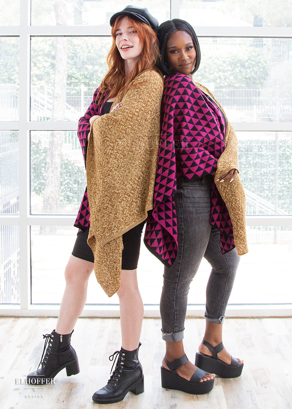 Chloe and Lynsi stand back to back with their arms crossed in front of their bodies, both wearing the dual patterned poncho.