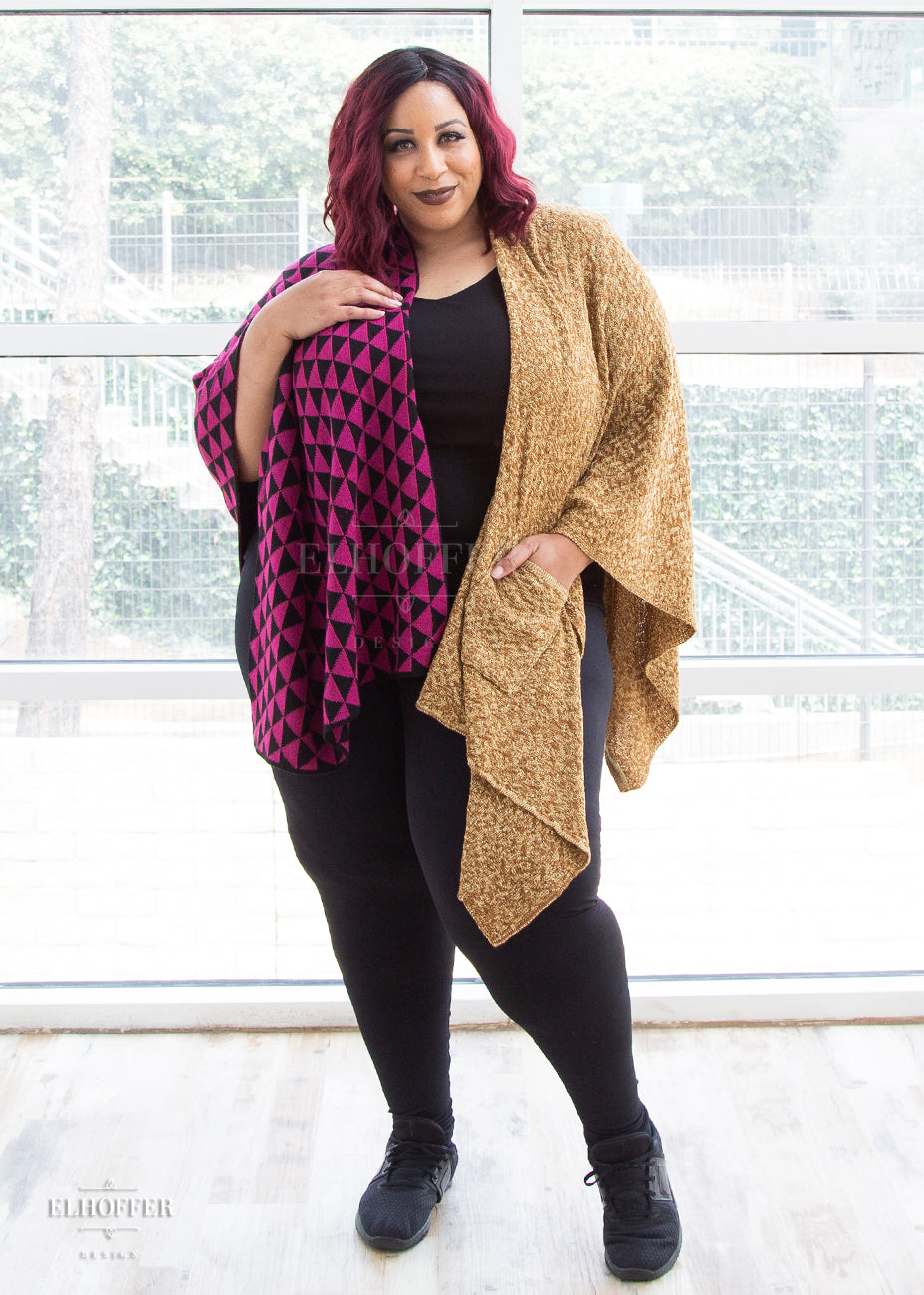Dawn, a dark haired medium skinned size 3X model, wears the pink, black, and golden mustard poncho. She pairs it with a black top, black leggings, and black sneakers.