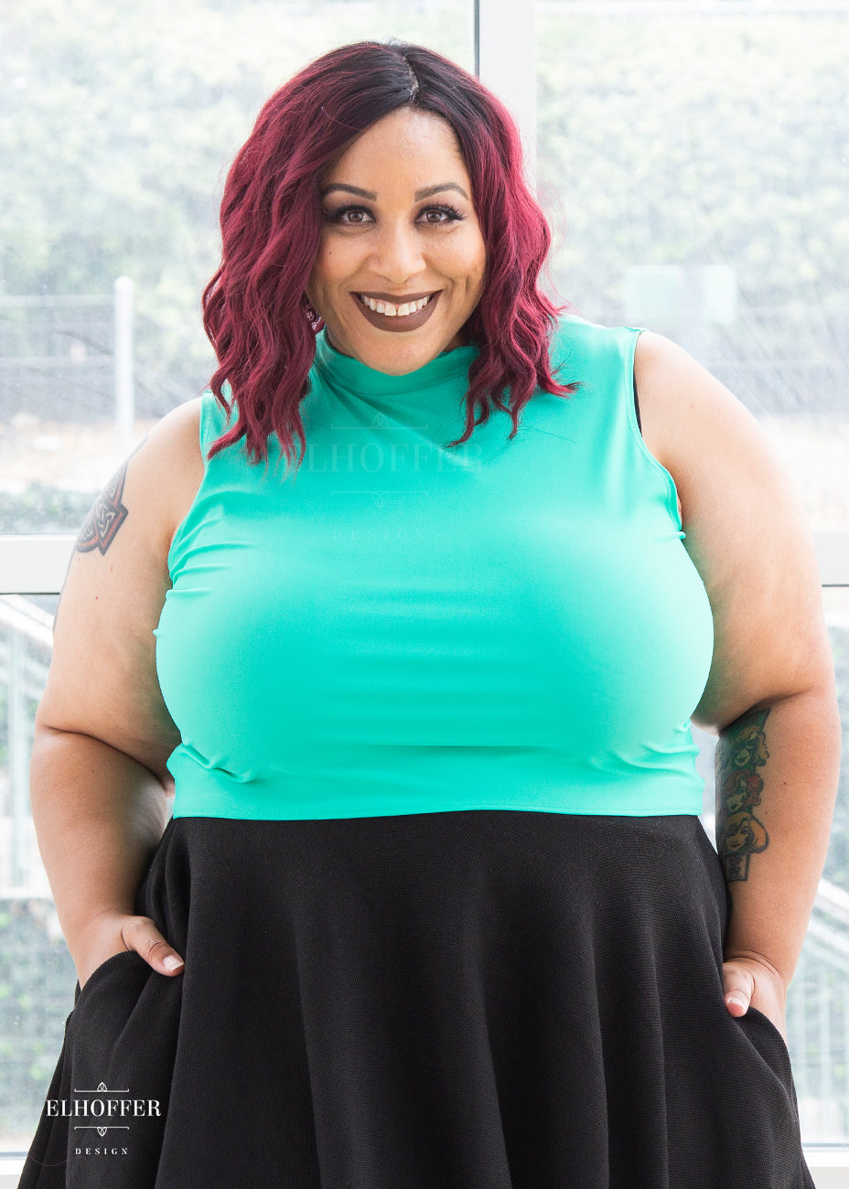Dawn, a medium-dark skinned 3X model with maroon ombre hair, models the mock turtle necked, mint green Jes crop top. She has paired it with our black knit skirt.