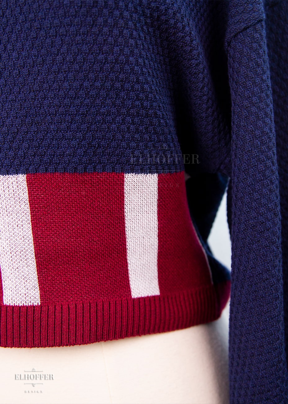Close up of blue waffle knit texture and red and white stripe detailing along waistliine.