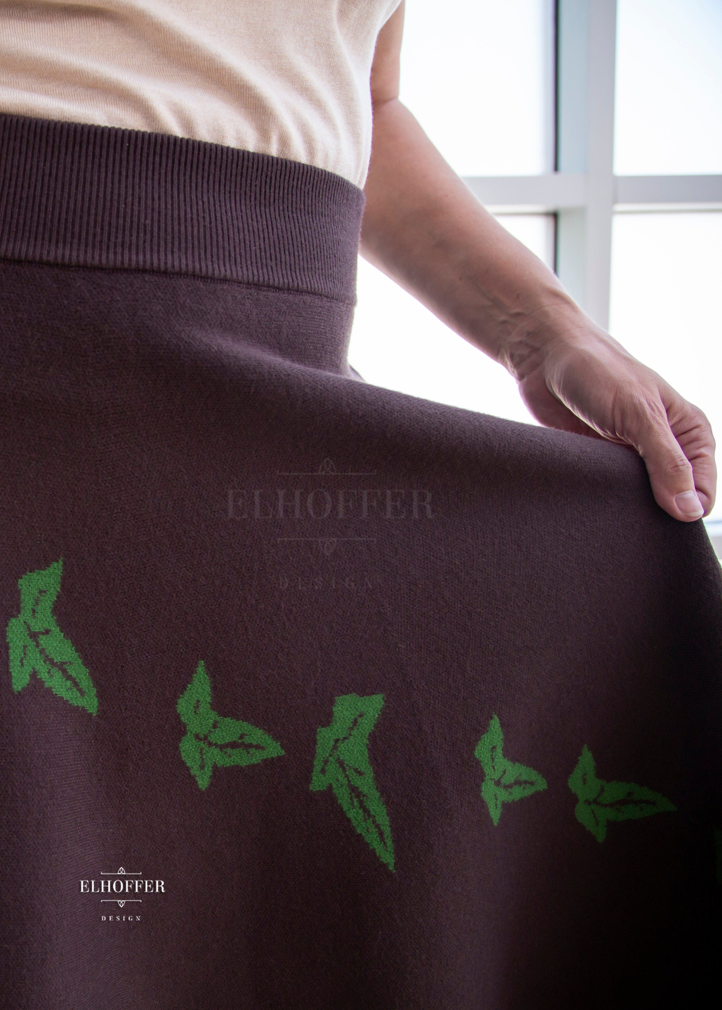 A close up of the green leaf design on the brown knit skirt