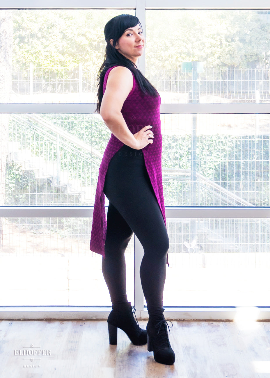 Lauren, a fair skinned size medium model with long black hair with side bangs, is wearing a pullover cropped sleeveless knit top with front and back flaps in a magenta triangle knit.