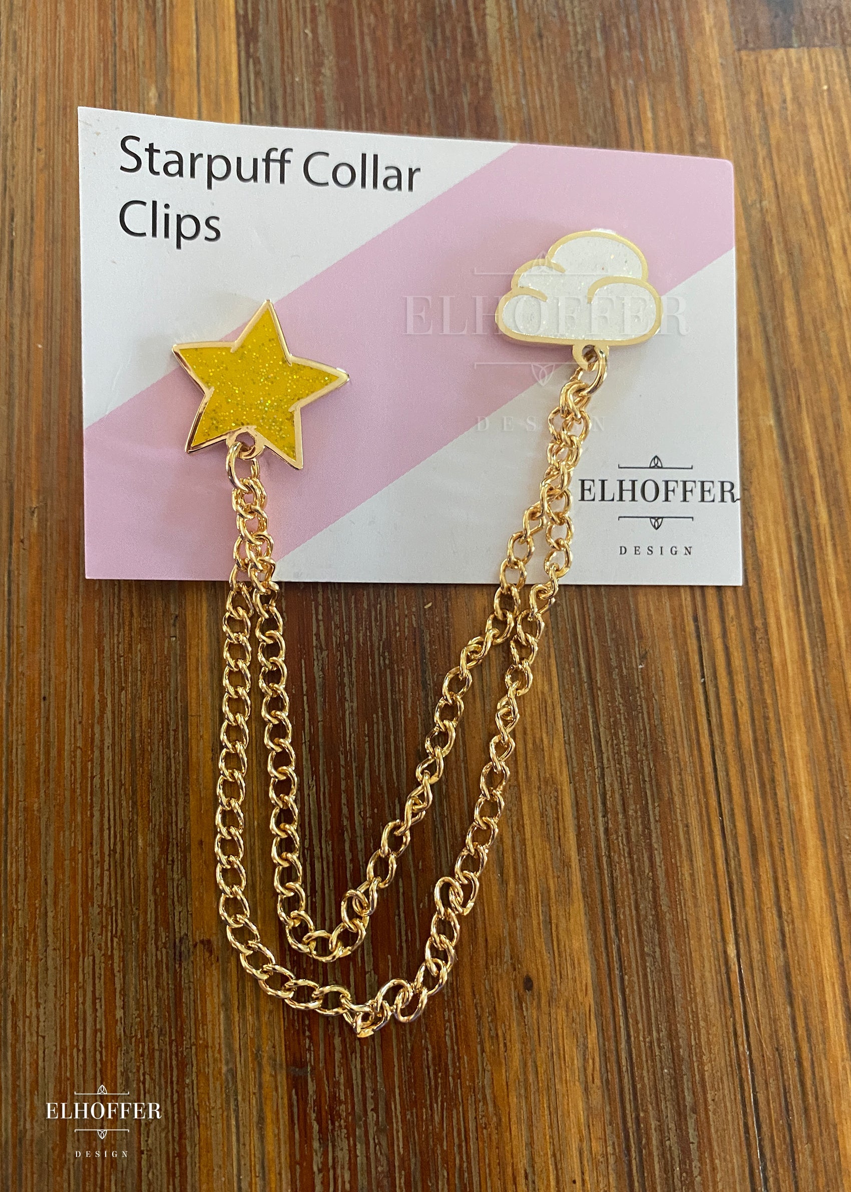 A tiny star pin and a tiny cloud pin connected together with 2 lengths of gold chain.